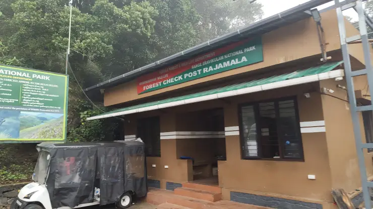The Forest Check Post Rajamala building has a green sign, a tiled approach and a small electric cart beside it.