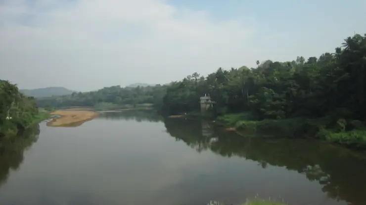 The Pamba bends between broad exposed rocks and wooded banks at Perunthenaruvi.