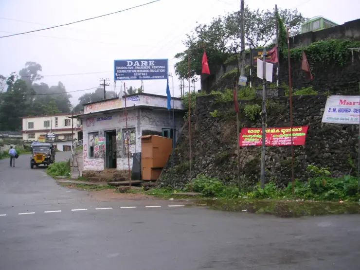 Peermade’s town junction, with vehicles, signs and mist beyond the street.
