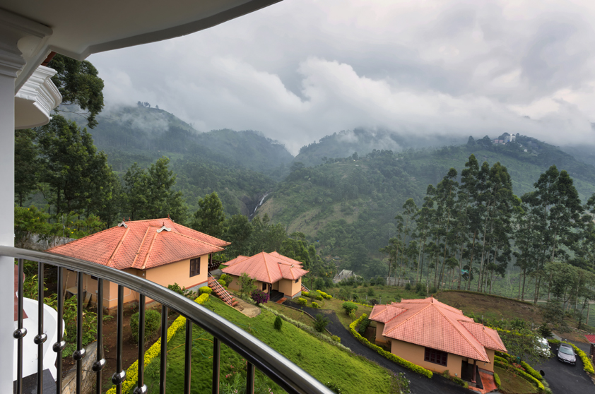 Red-roofed cottages and gardens viewed from a balcony at Aranyaka Resort