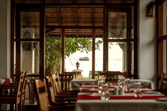 Dining tables and open waterfront doors at Choola, Punnamada Resort