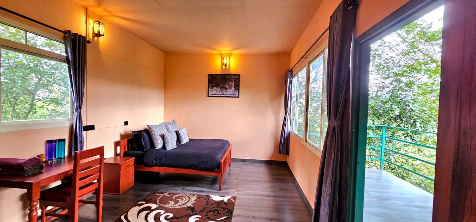 Jungle Retreat’s treehouse bedroom and balcony doorway; other accommodation categories have different settings.
