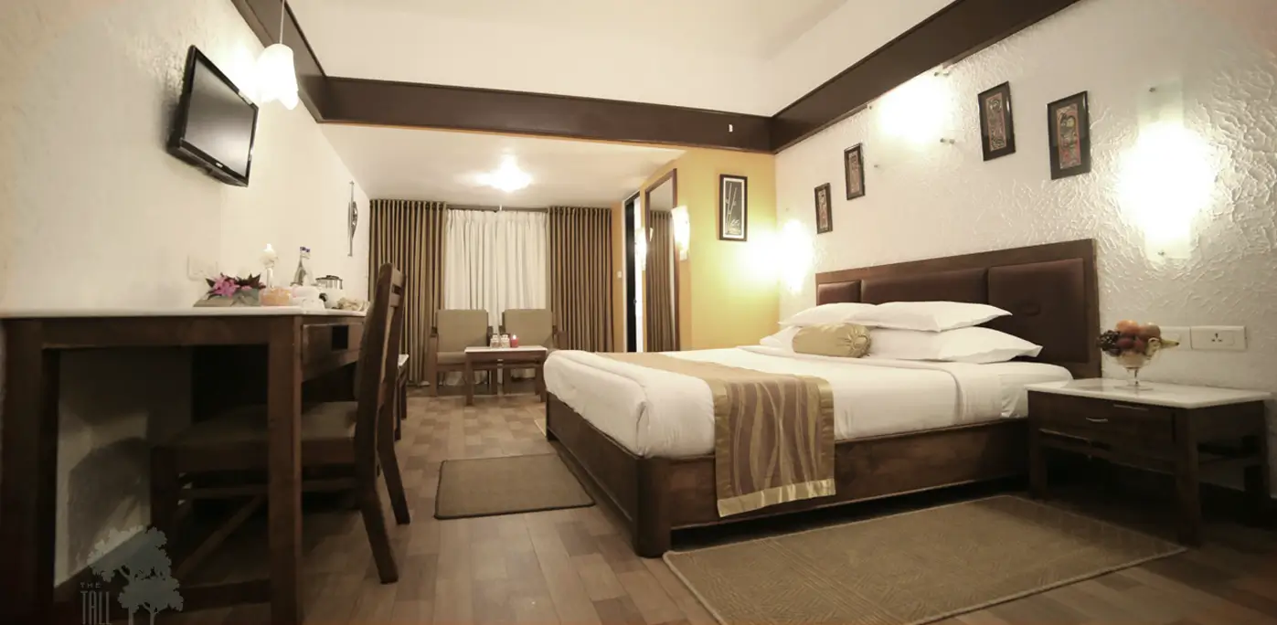 Bed, desk and seating in a Cinnamon Cottage bedroom at Tall Trees Munnar
