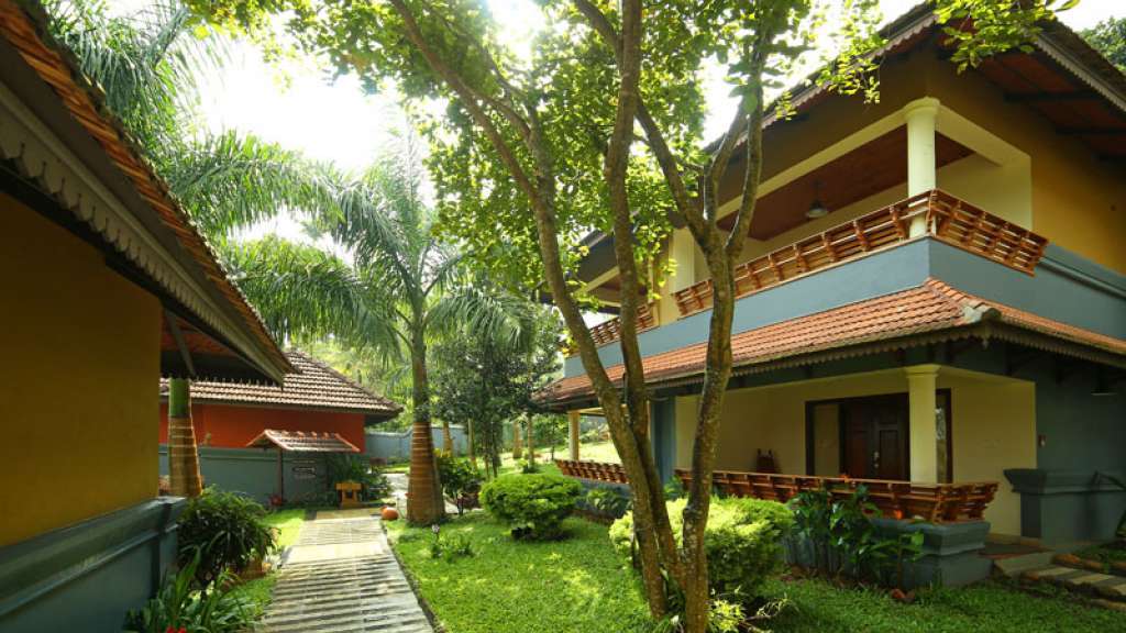 A shaded garden walkway between buildings at The Elephant Court in Thekkady.