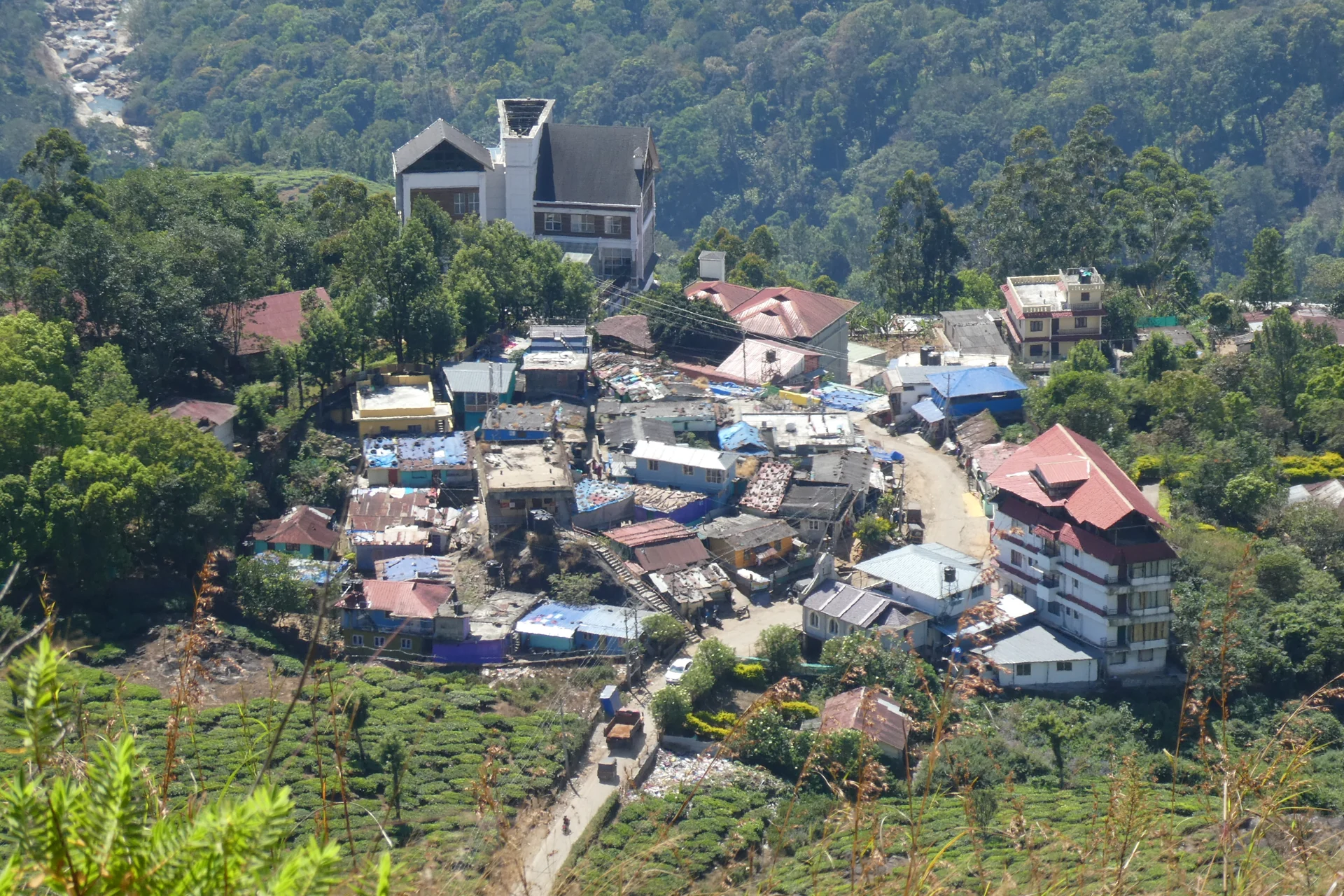 Colourful roofs and a curving road in Pothamedu village, surrounded by tea slopes.