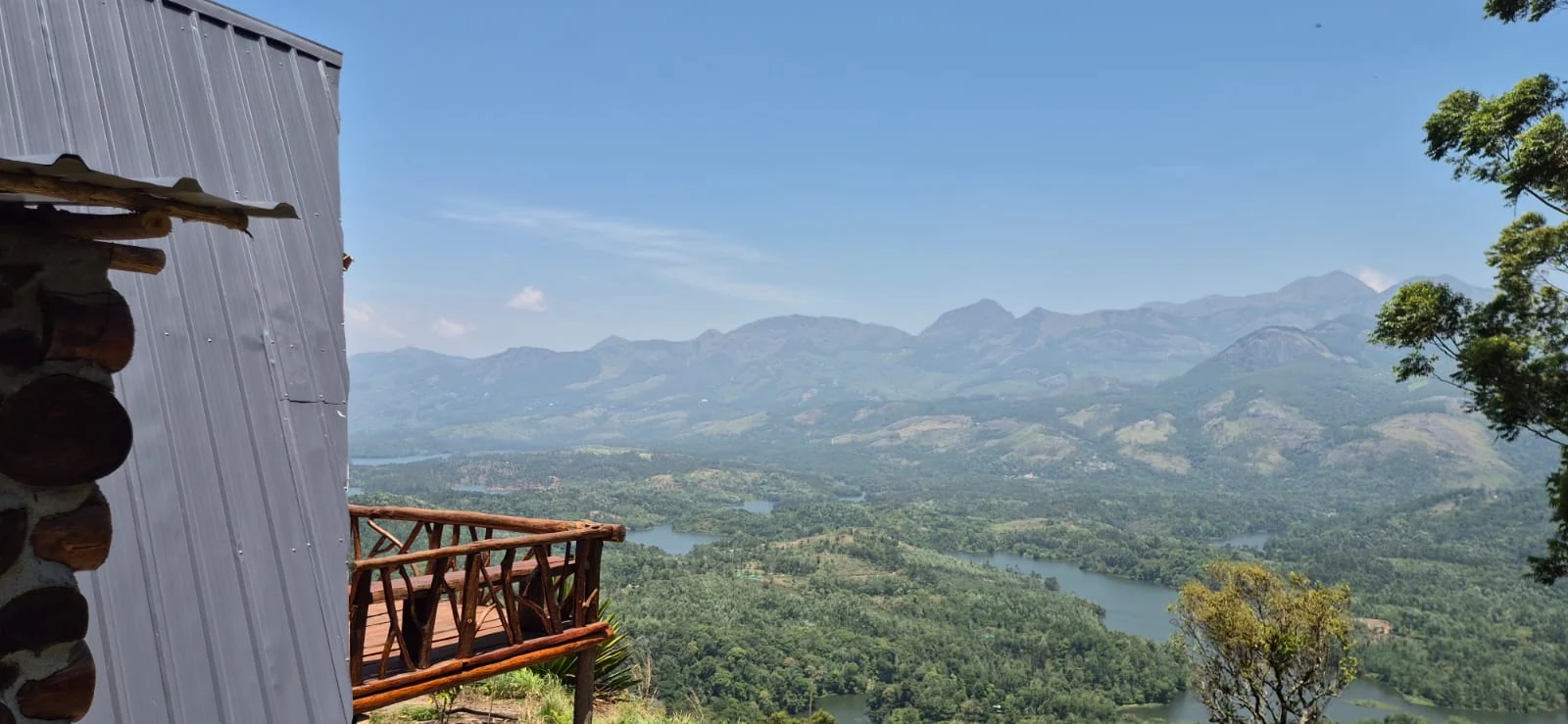 The balcony of Chundal A Frame Log House overlooks Anayirankal reservoir and distant hills.