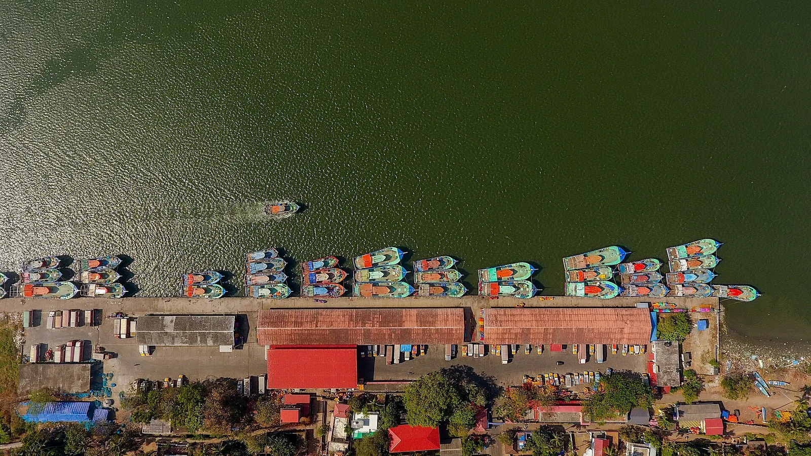 Aerial view of trawlers moored in ranks along the quay at Munambam fishing harbour