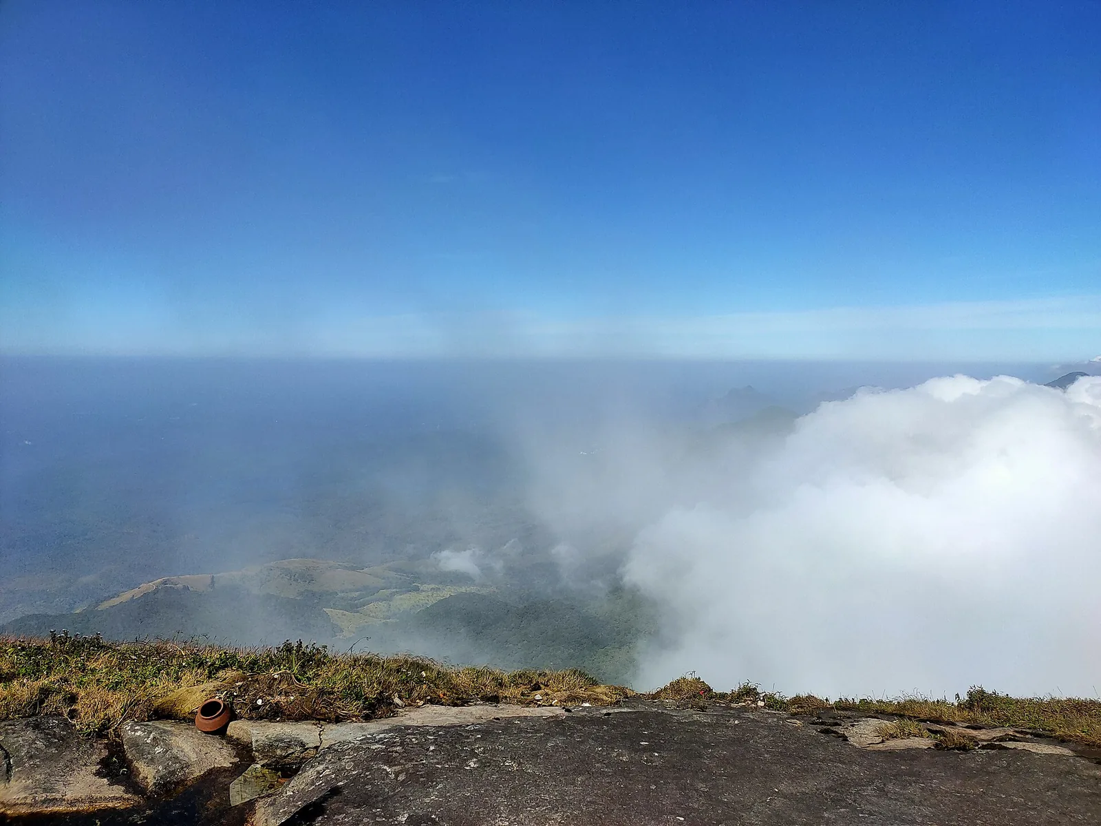 The summit of Agasthyakoodam above a bank of cloud, with a small clay offering pot on the bare rock