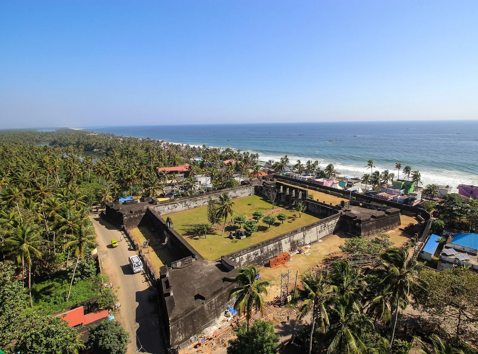 Aerial view of Anchuthengu Fort, a walled rectangle with corner bastions on a narrow strip between the Arabian Sea and a backwater