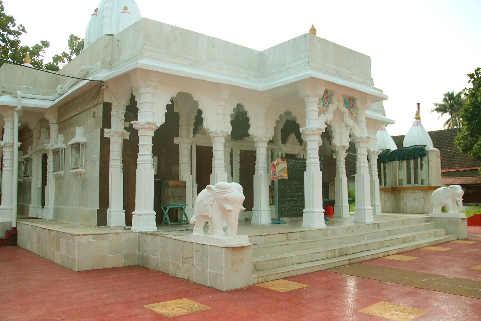 The white marble Swetamber Jain temple at Alappuzha, with carved pillars, a stepped porch and two carved marble elephants flanking the entrance