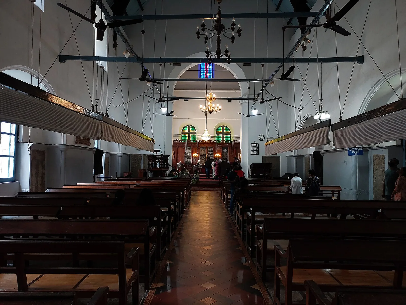 The bare whitewashed nave of St Francis Church, Kochi, with wooden punkah frames slung above the pews