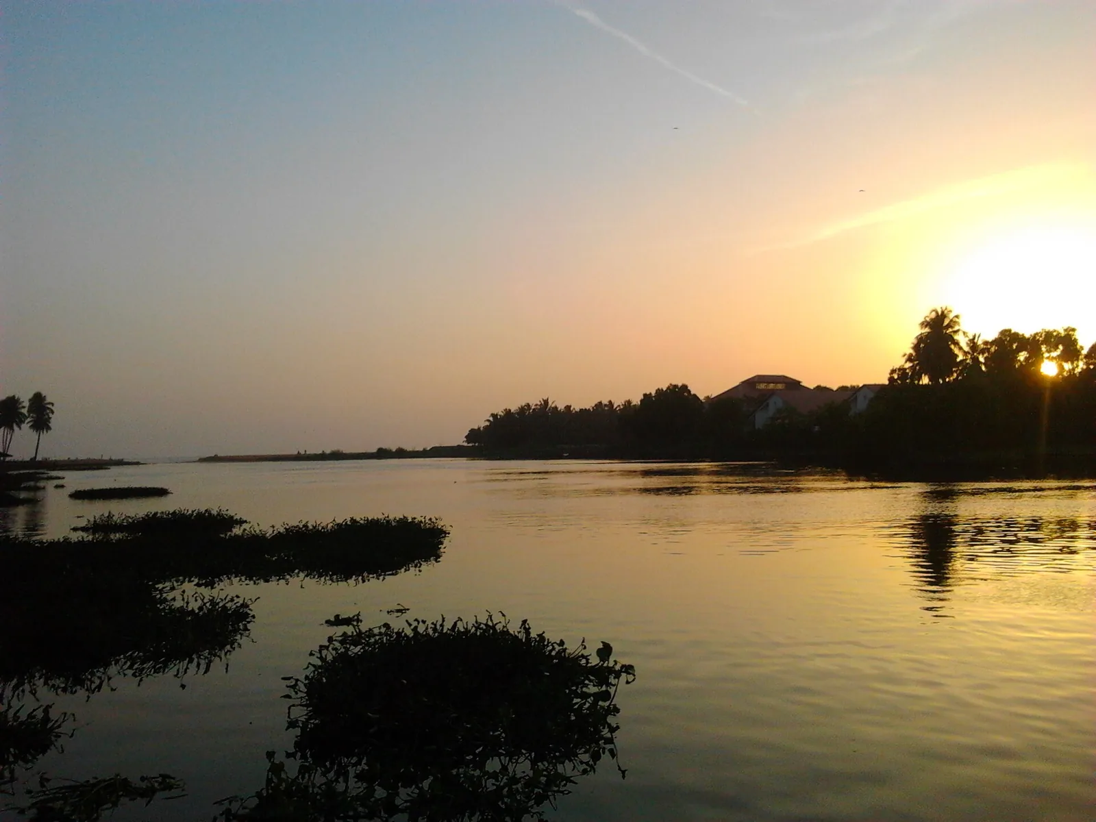 Sunset over Veli lagoon with weed islands in the foreground and the tourist village buildings silhouetted on the far bank