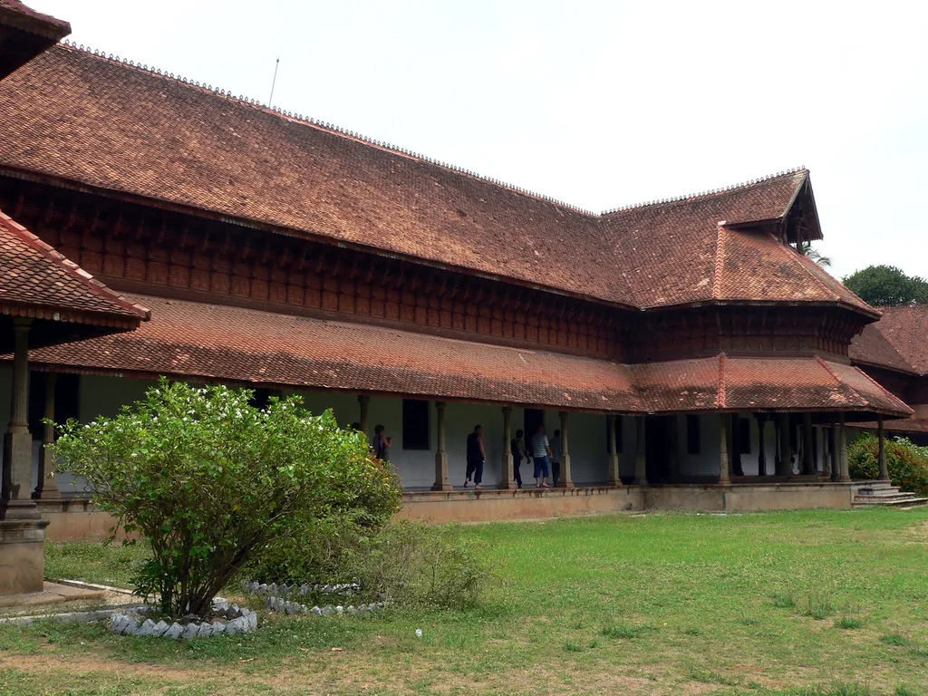 The pillared verandah of Kuthiramalika palace with visitors walking along it, seen across the lawn under the deep tiled roof