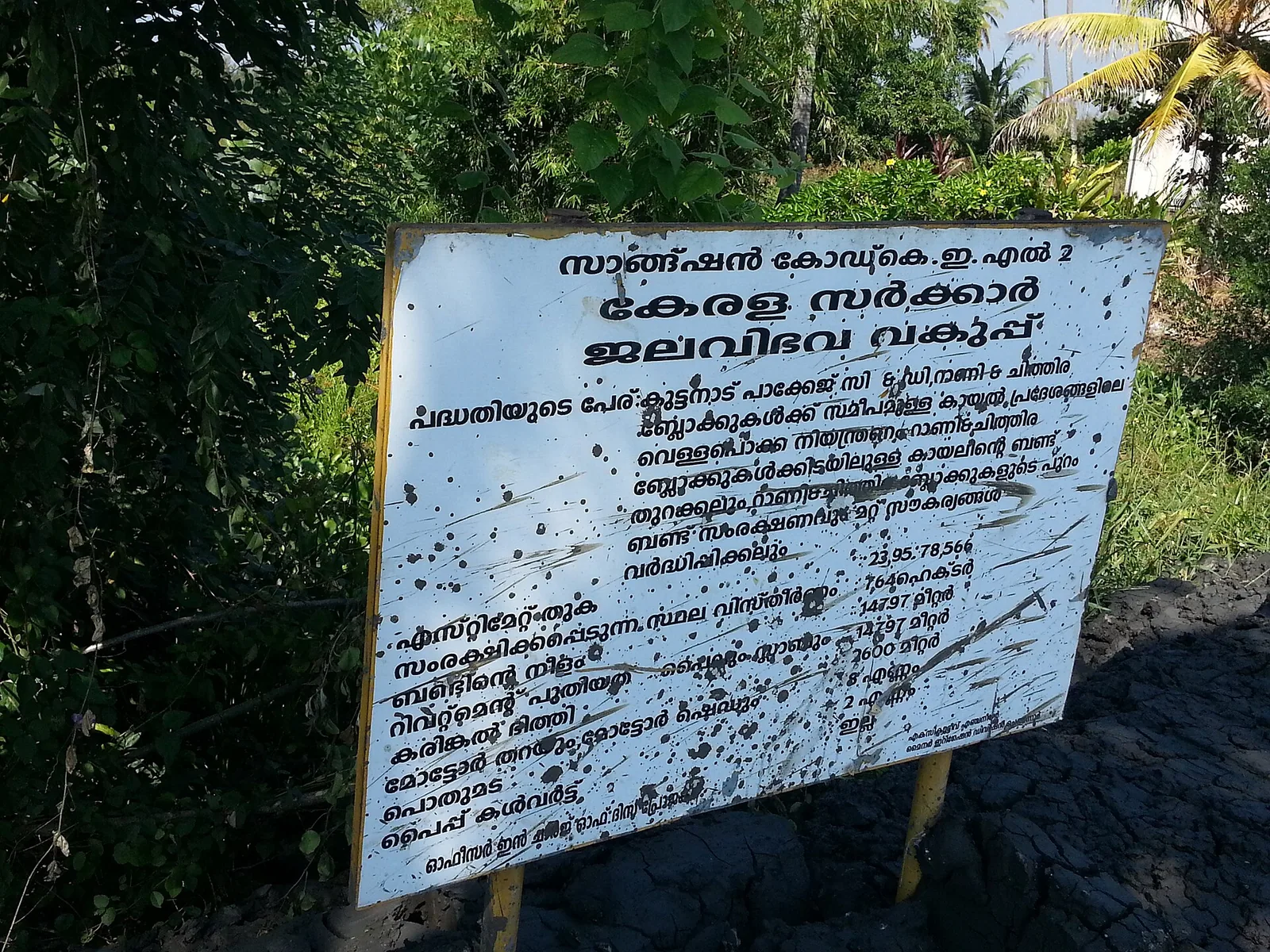 A weathered Kerala Water Resources Department project board at R Block, lettered in Malayalam with a list of quantities