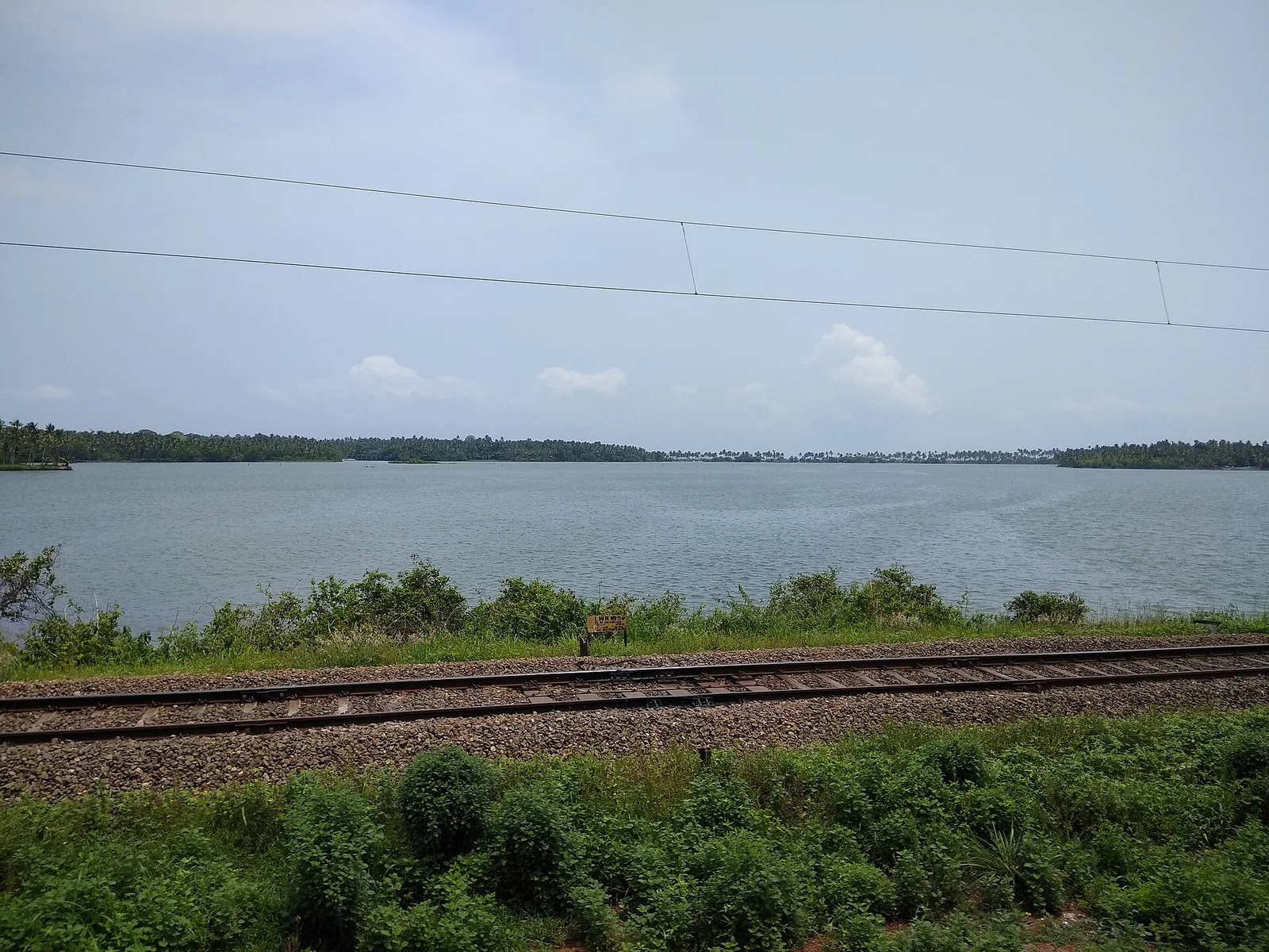 Paravur Kayal, the backwater lake behind the coastal ridge at Paravur, with palm-lined banks.