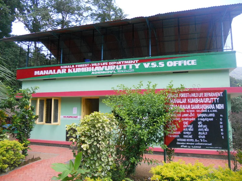 A small green and red building signed Manalar Kumbhavurutty V.S.S Office, Achenkovil, with a hand-painted tariff board on a post beside it.