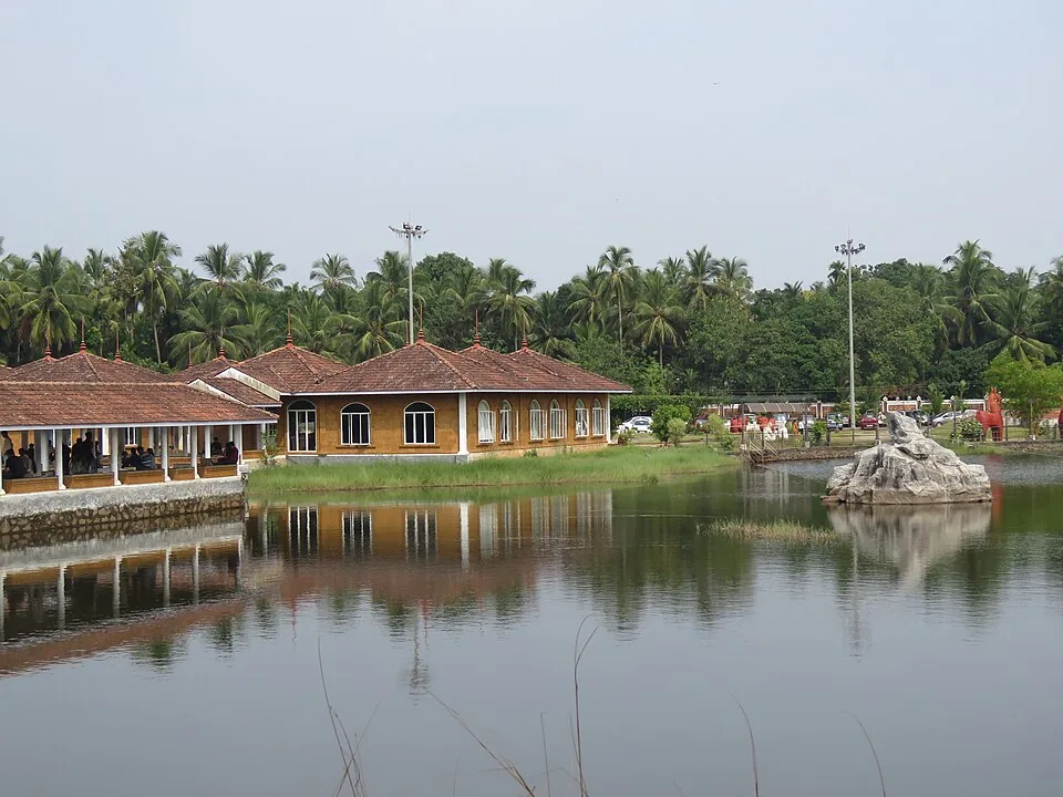 A tiled, veranda-fronted laterite pavilion at Sargaalaya, Iringal, standing above the still water of the campus quarry lake