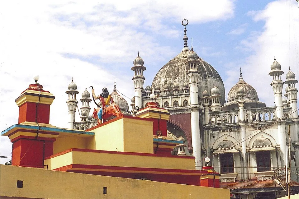 Temple roof and Ayyappa figure in front of the domes of Erumely Vavar mosque
