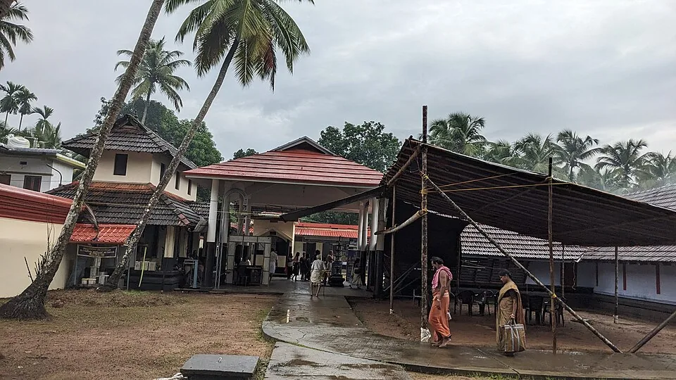 The courtyard of the Alathiyur temple on a wet morning with tiled ranges and worshippers crossing