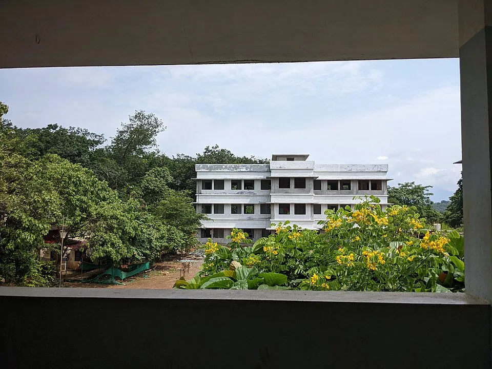 The Aralam Farm Higher Secondary School, a long white building standing among trees on the farm land in Kannur