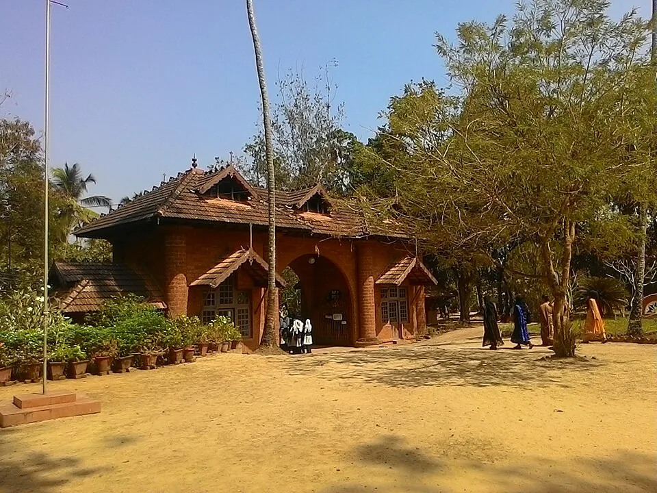 The open sandy courtyard at Thunchan Parambu with tiled buildings behind and visitors walking across it