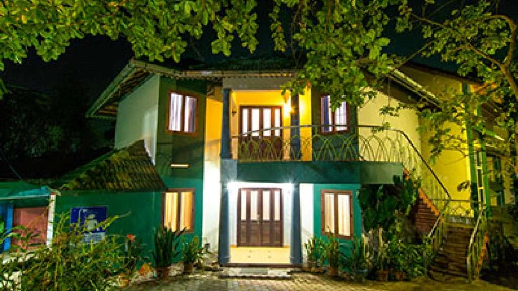Haritagiri’s green-and-white accommodation building is lit at night, with an upper balcony and an outside staircase.