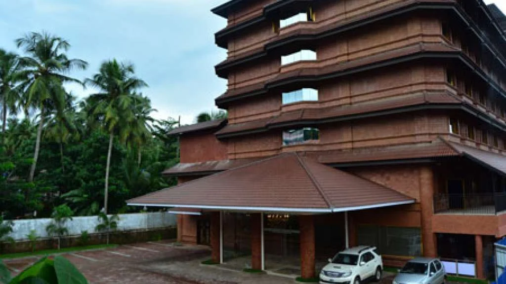Park Residency’s reddish-brown building rises above a broad entrance canopy and a forecourt with parked cars.