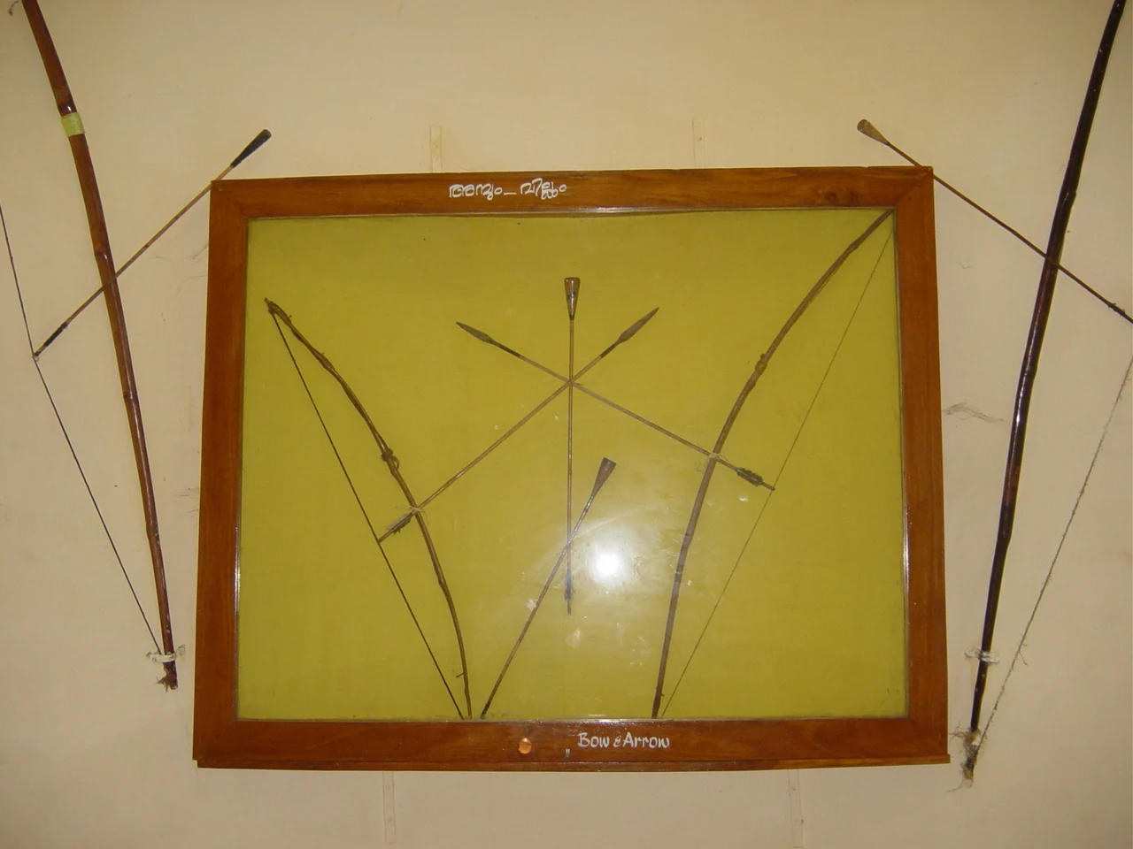 Bows and crossed arrows are displayed in a framed glass case at the museum beside Pazhassi’s tomb.