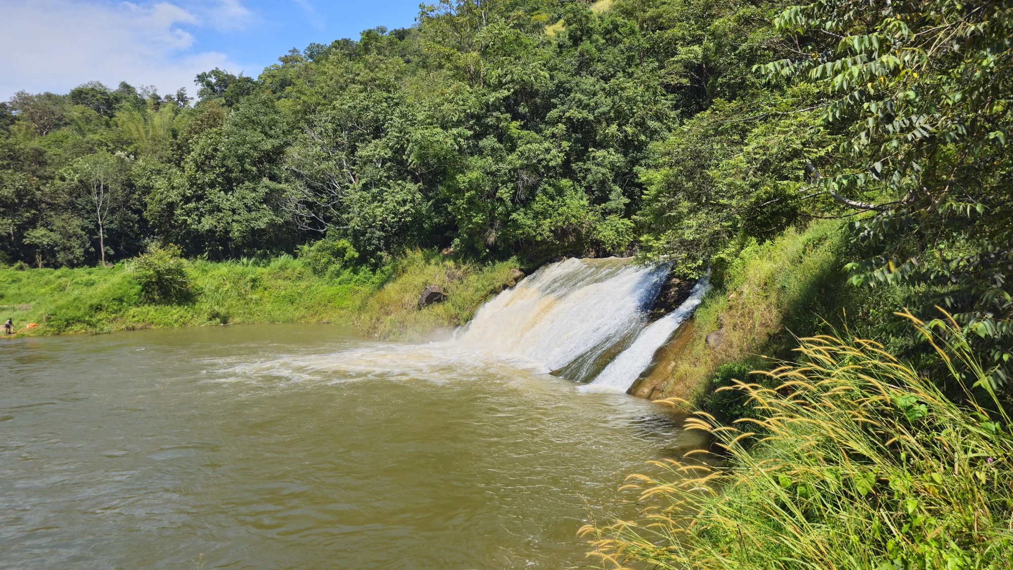 White water spreads over Anchuruli’s rock slope before entering brown-green reservoir water