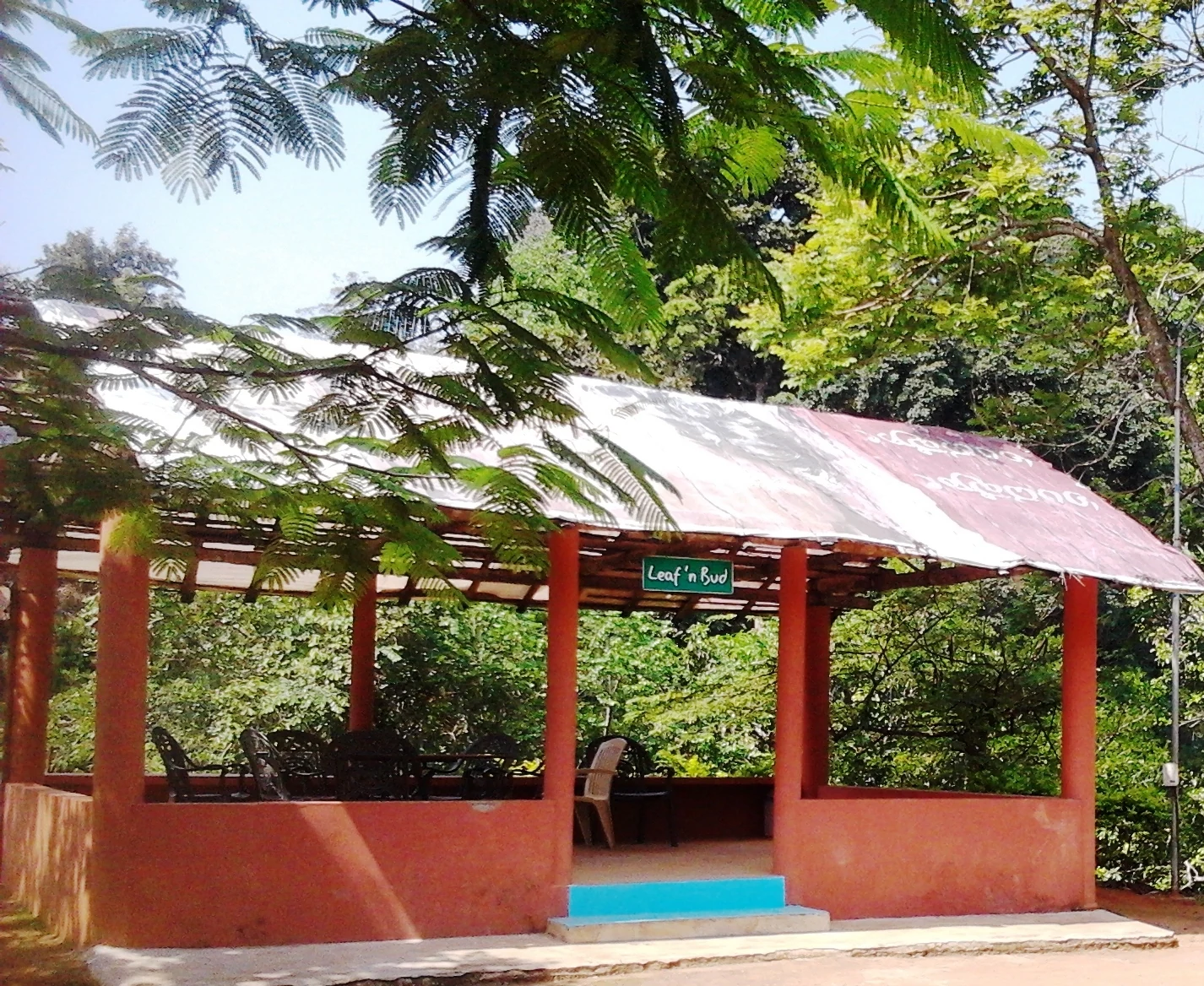 An open-sided red-orange shelter with a metal roof and Leaf n Bud sign near Vaduvanchal Meenmutty in 2014