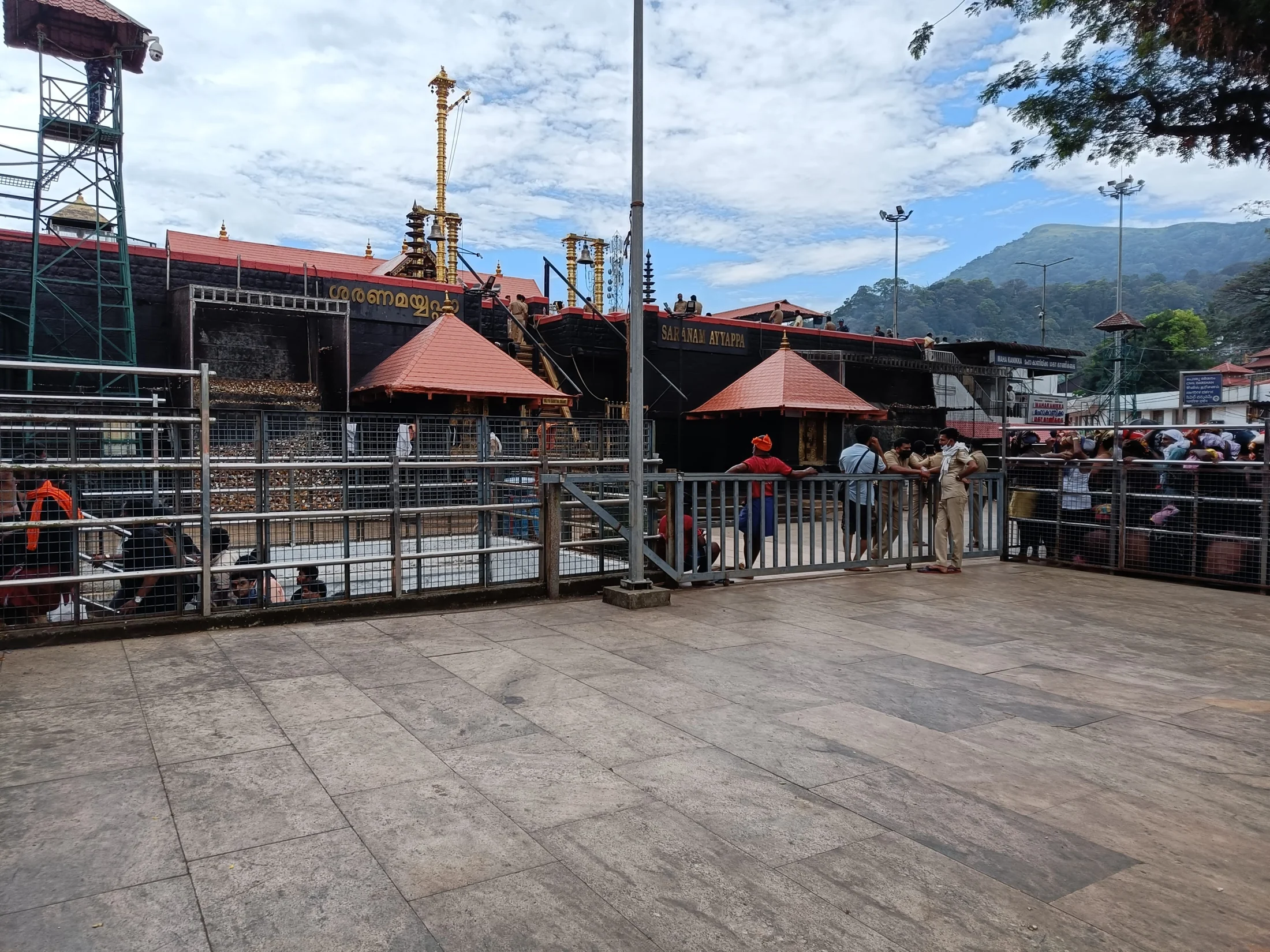 The outer wall, flagstaff and layered roofline of the Sabarimala temple precinct.