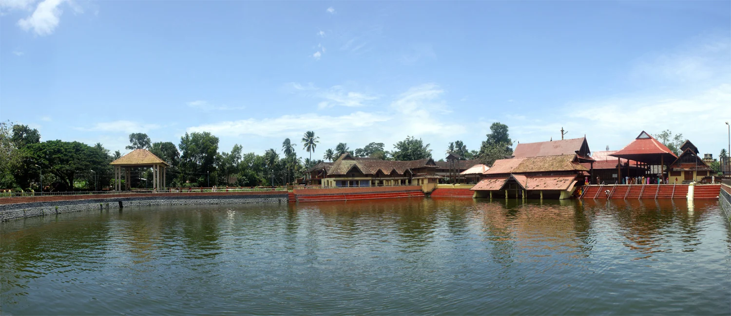 The temple tank reflects Ambalappuzha’s long tiled roof and surrounding buildings.