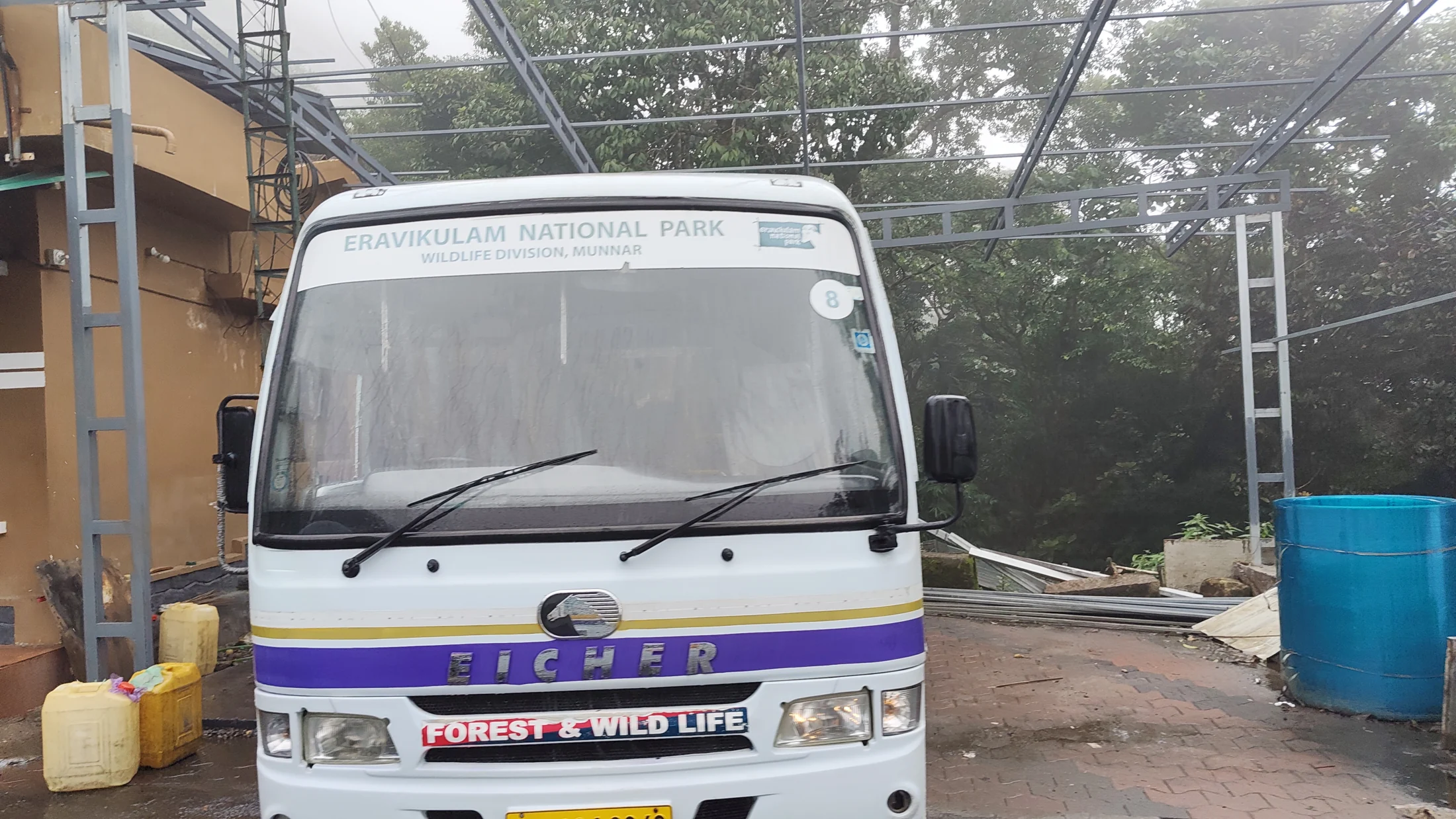 An Eravikulam National Park passenger bus stands on the upper Rajamala road with hills behind it.