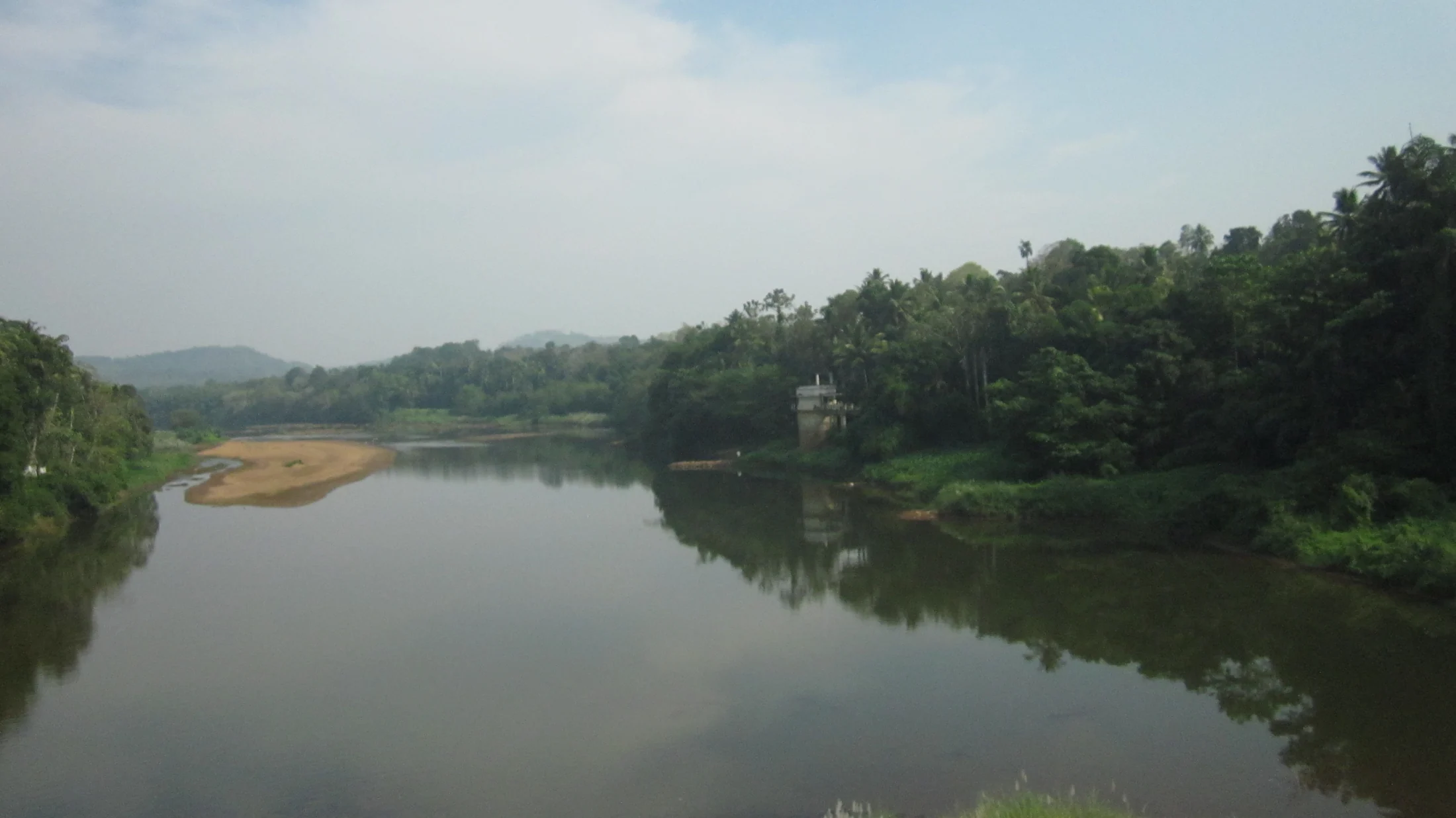 The Pamba bends between broad exposed rocks and wooded banks at Perunthenaruvi.