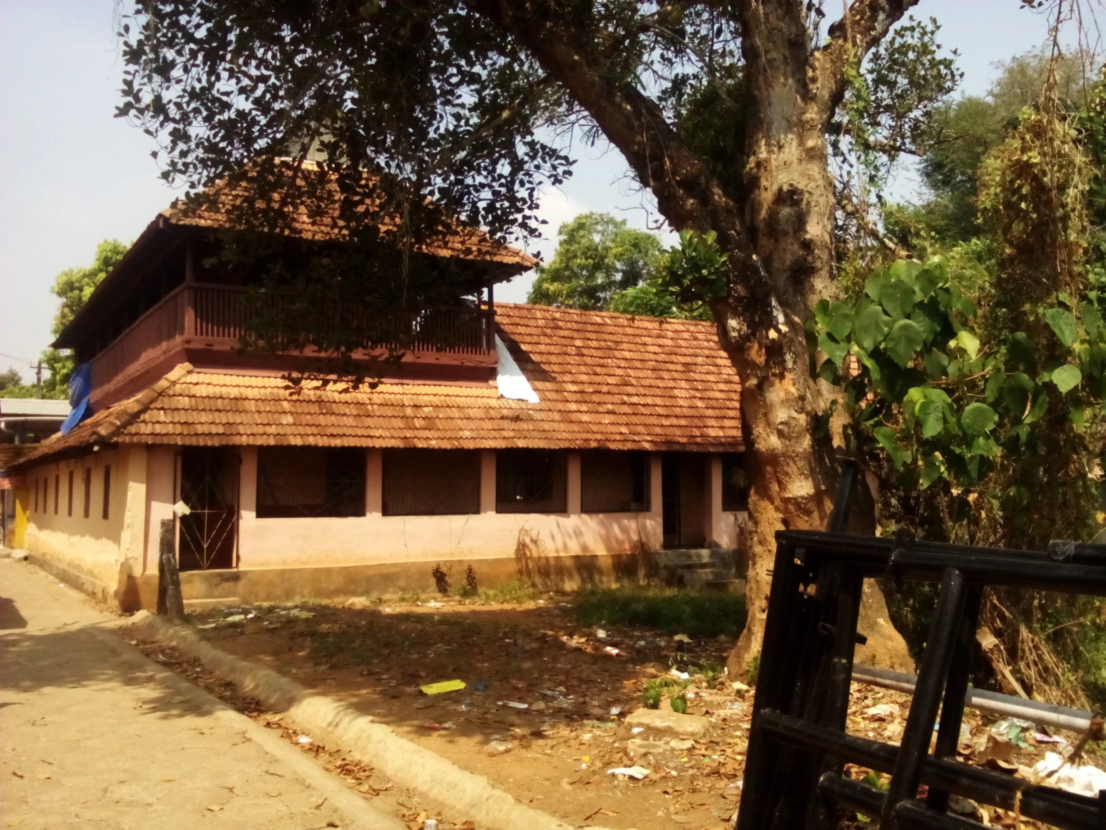 A large tree stands beside a tiled-roof palace building at Pandalam.
