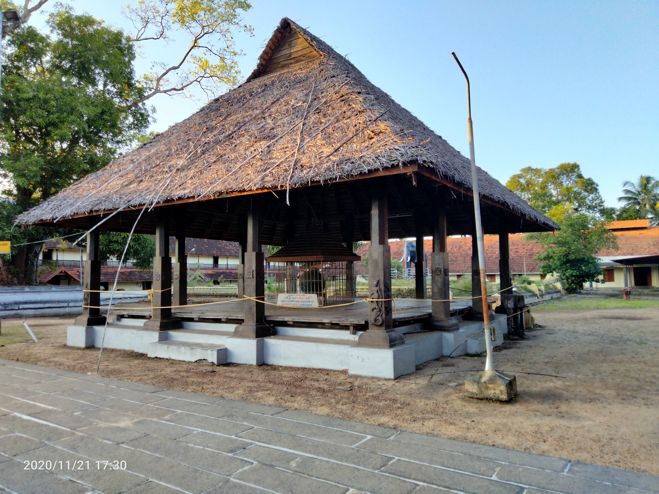 A steep-roofed pavilion stands within Ambalappuzha’s temple setting, with steps and timber details beneath the eaves.