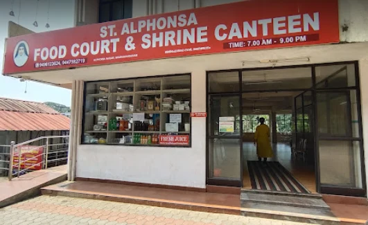 The signed entrance to St Alphonsa Food Court and Shrine Canteen, with its counter and glass doors.