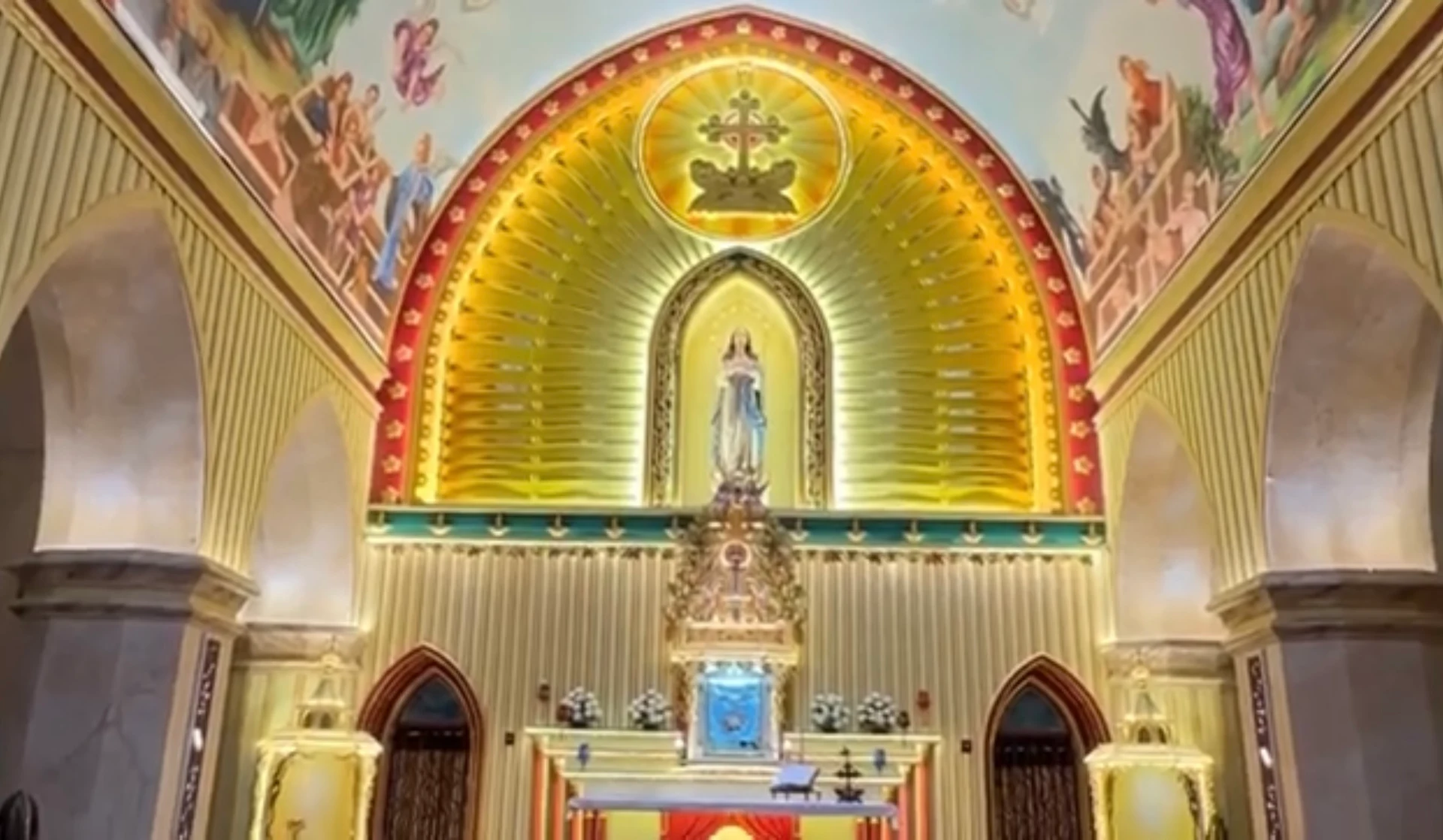 The parish sanctuary’s Marian figure, radiating gold backdrop and painted arched surround.